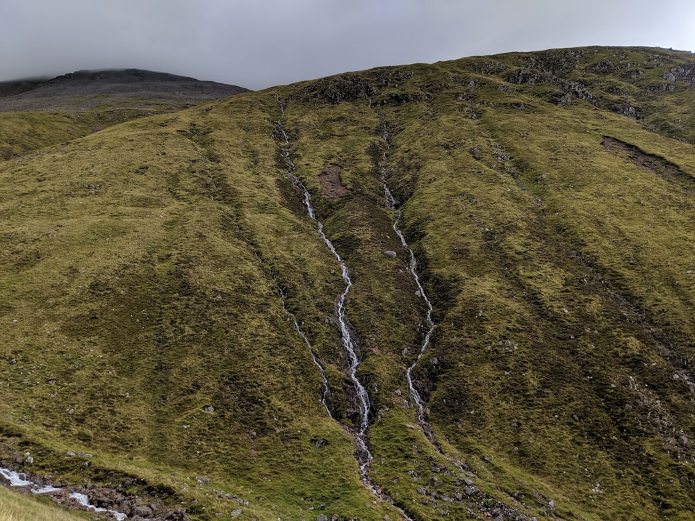 a large green hill with a waterfall