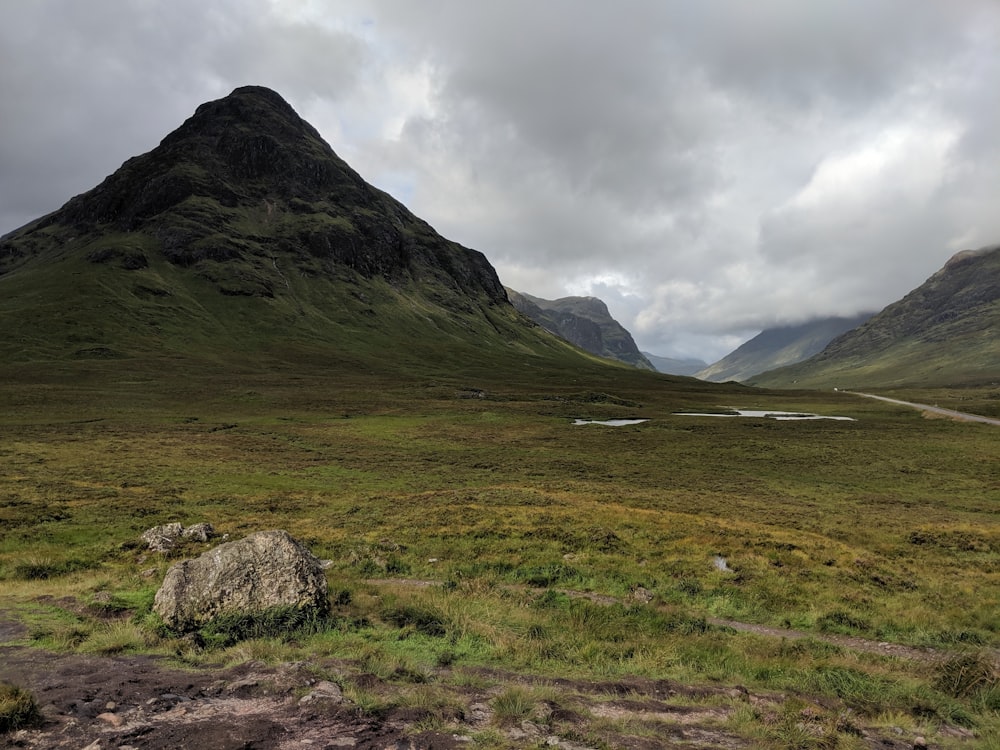 a grassy valley with mountains in the background