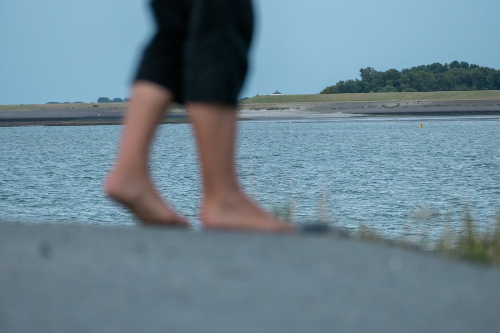 les jambes d’une personne sur un rebord au-dessus de l’eau;