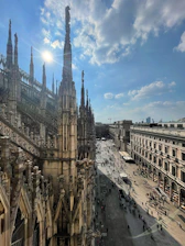 A bright, sunny view of the Duomo di Milano with people admiring its gothic spires.