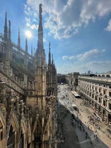A bright, sunny view of the Duomo di Milano with people admiring its gothic spires.
