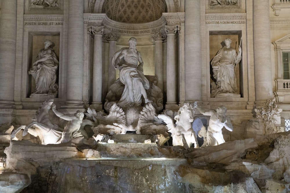 a fountain with statues in front of Trevi Fountain