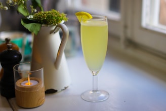 a glass of green liquid with a lemon slice on a table