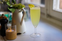 a glass of green liquid with a lemon slice on a table