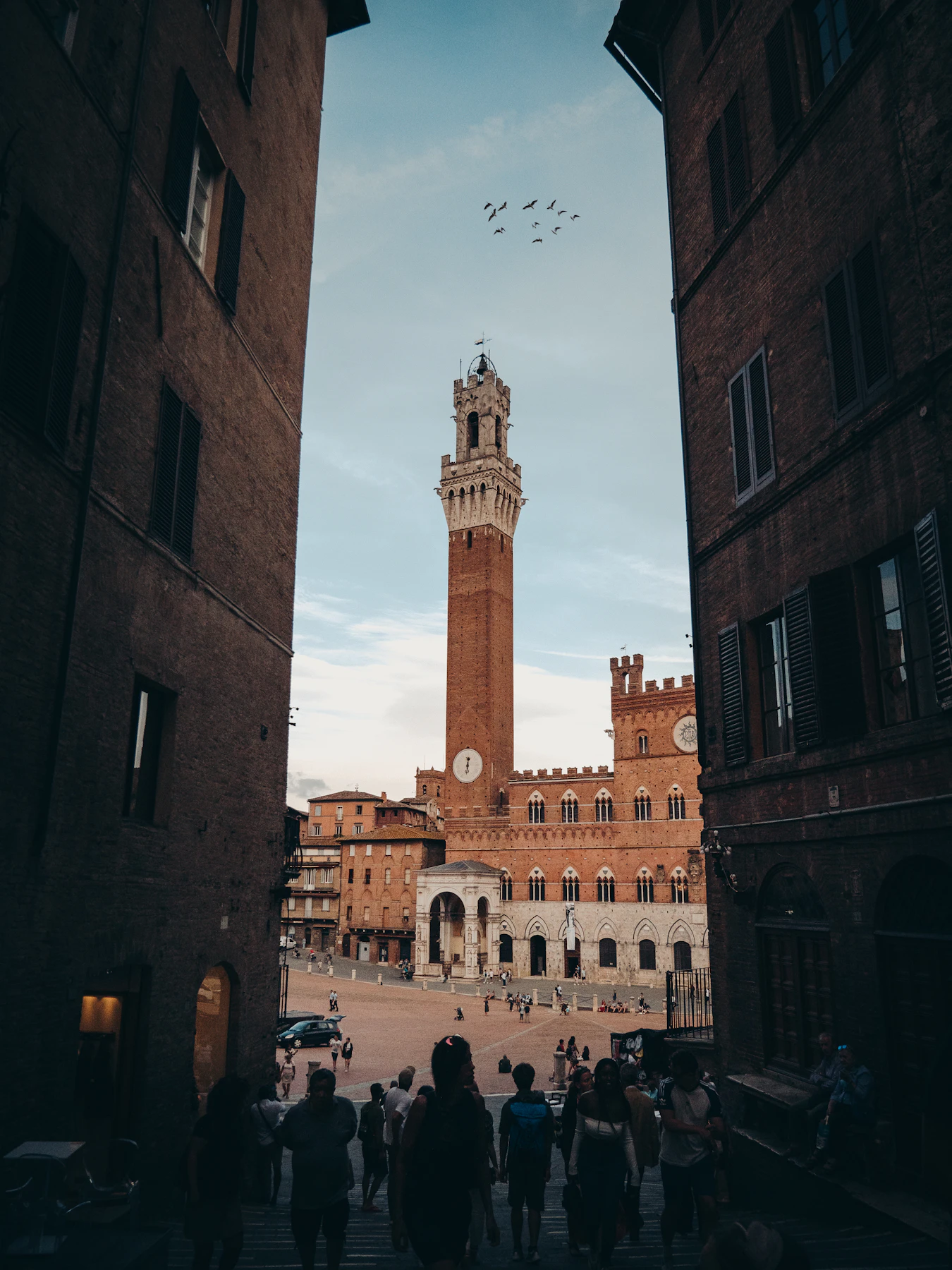 Mensen wandelen door een straat bij Piazza del Campo in Siena