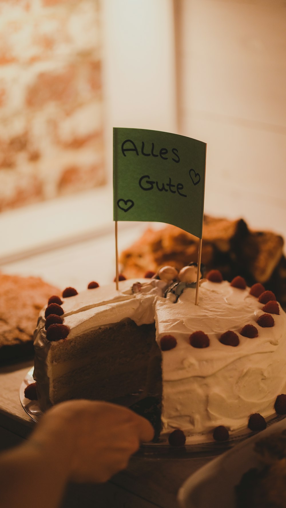a hand holding a sign above a cake
