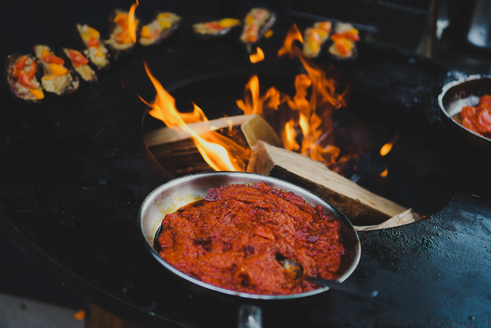 A pan of food flaming over the fire