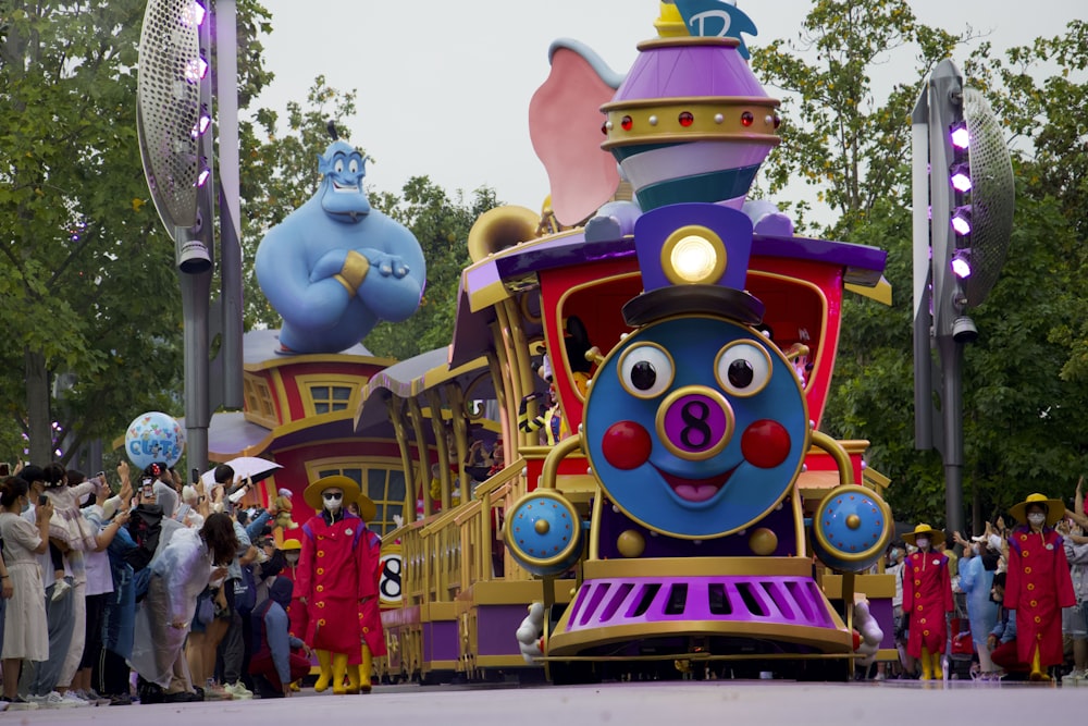 a group of people standing around a colorful amusement park ride