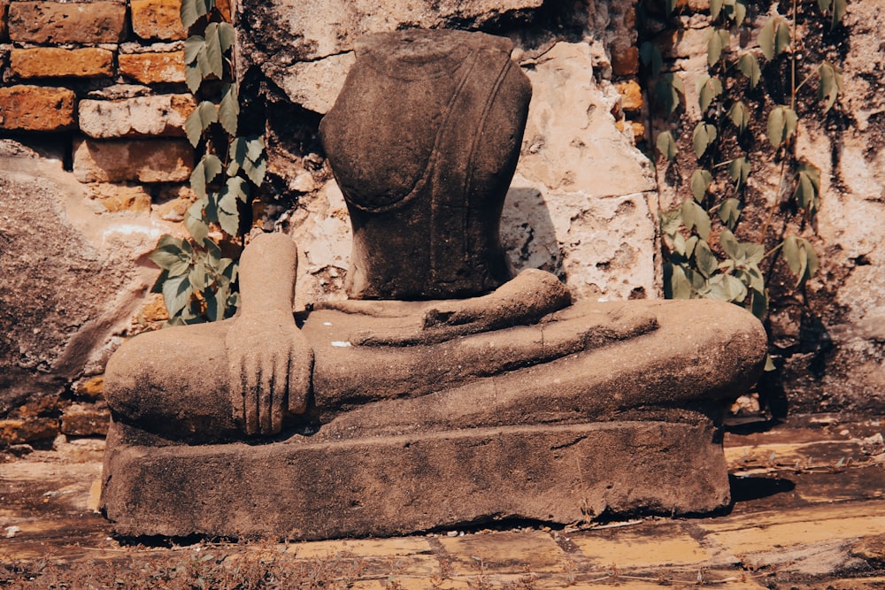 a stone wall with a statue of a person sitting on a rock