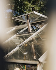 Technician repairing a greenhouse frame with tools on a sunny day.
