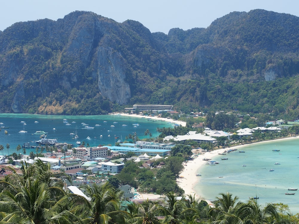 a beach with many boats and buildings with Phi Phi Islands in the background