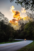 Sunset view over a quiet village road, with a motorbike silhouette against colorful skies.