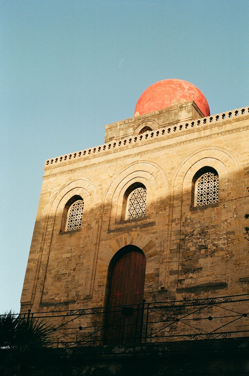 un gran edificio de piedra con San Cataldo, Palermo al fondo