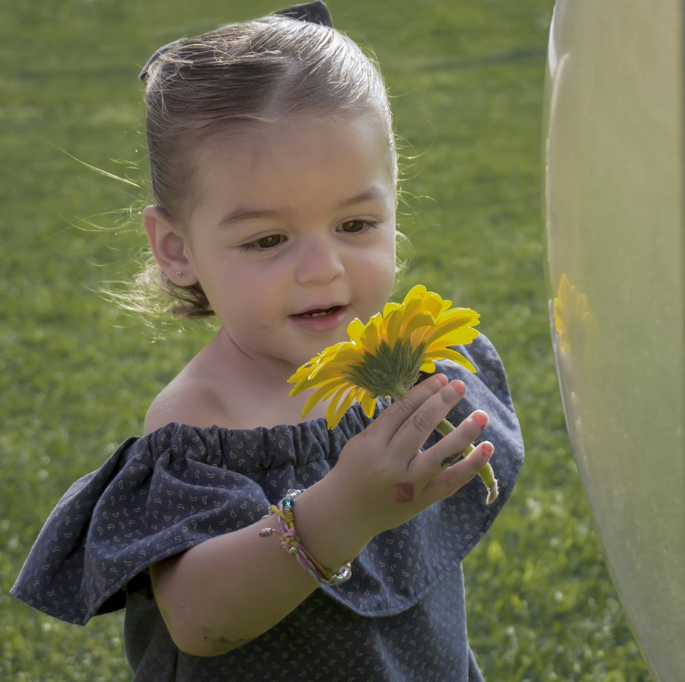 a young girl holding a yellow flower