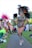 A person is walking along a path dressed in a vibrant and elaborate carnival costume with intricate beadwork and large feathered headgear. The costume features a leopard print design. In the background, other participants in colorful outfits are visible, preparing for an event.