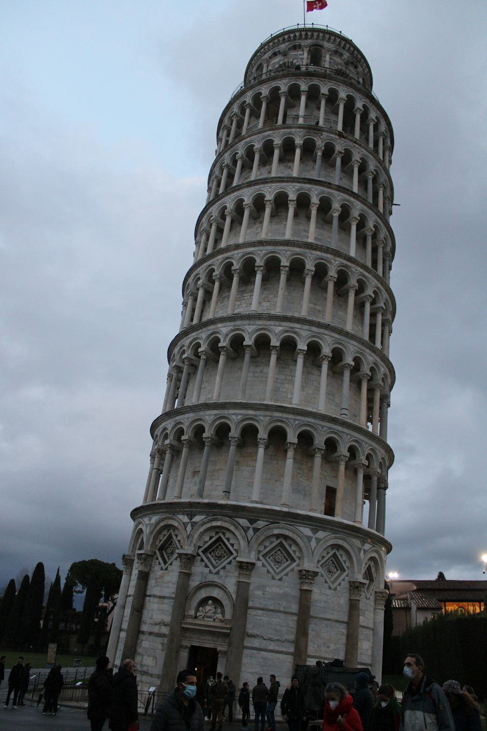 uma grande torre com pessoas ao redor dela com Torre Inclinada de Pisa ao fundo