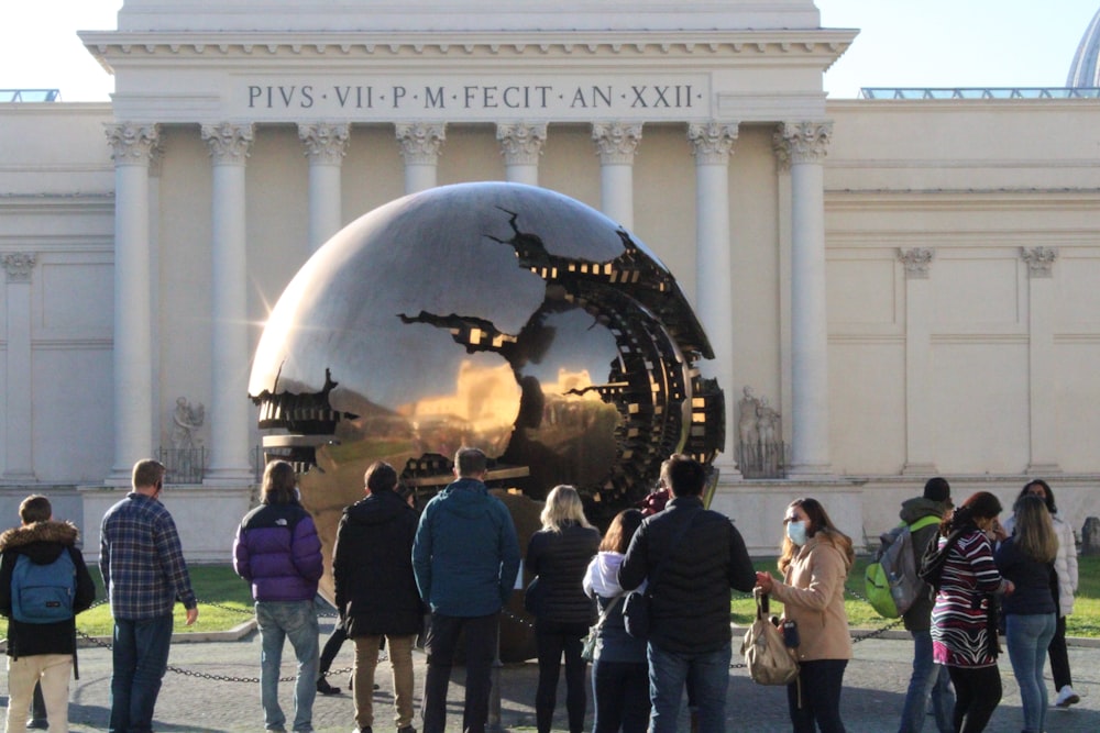 a group of people standing in front of a building with a large globe