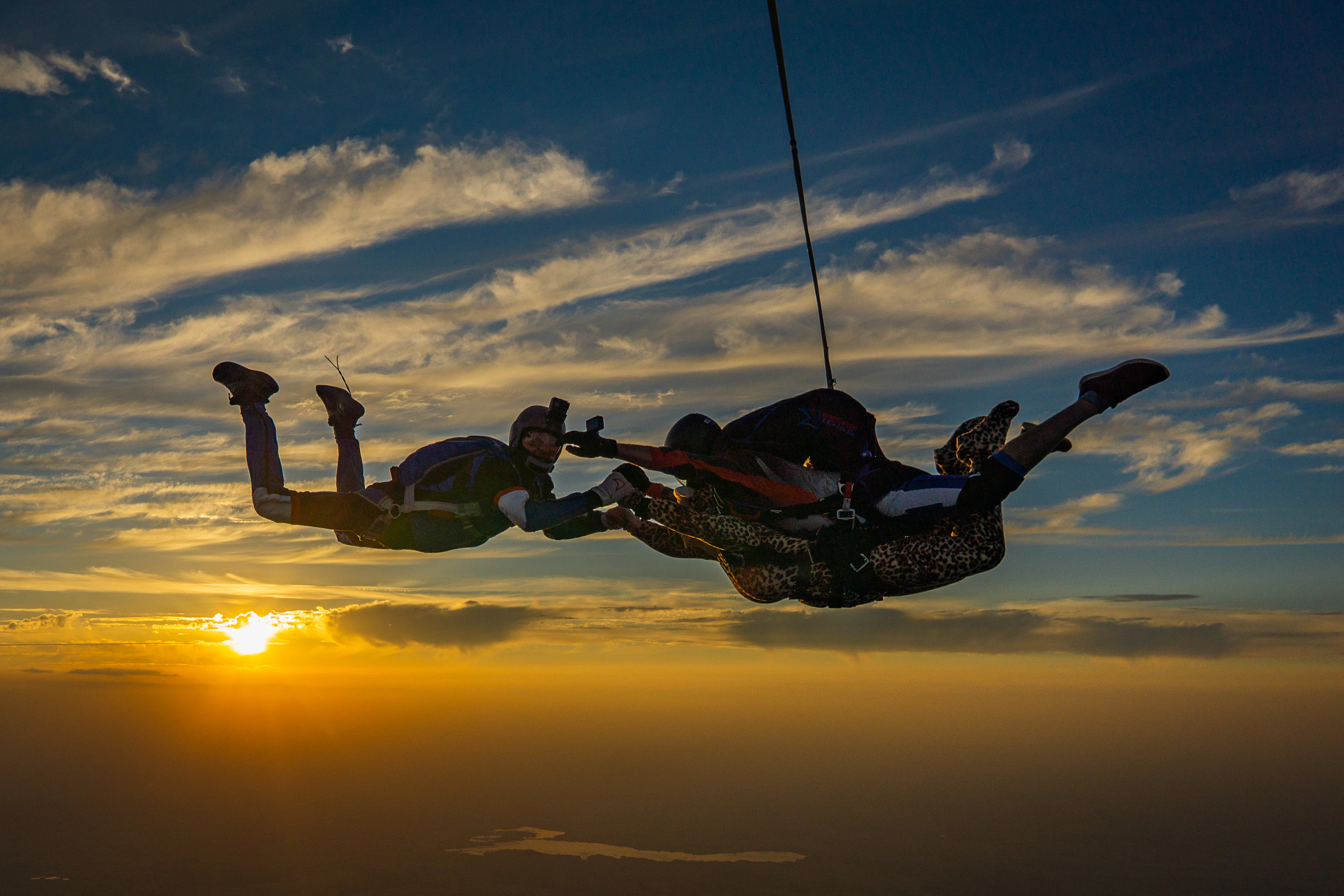 Tandem skydivers in freefall against a golden sky