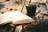 A close-up of a well-worn paperback thriller novel resting on a rustic wooden table beside a steaming cup of coffee.