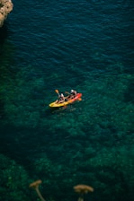 a group of people in a yellow kayak on a body of water