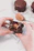 Close-up of a hand holding a freshly packed CJ Protein Snack with a creamy red background.