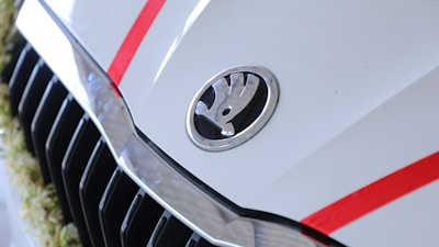 Close-up of a shiny red car's front grille with the grmotors-lazio logo in the background.