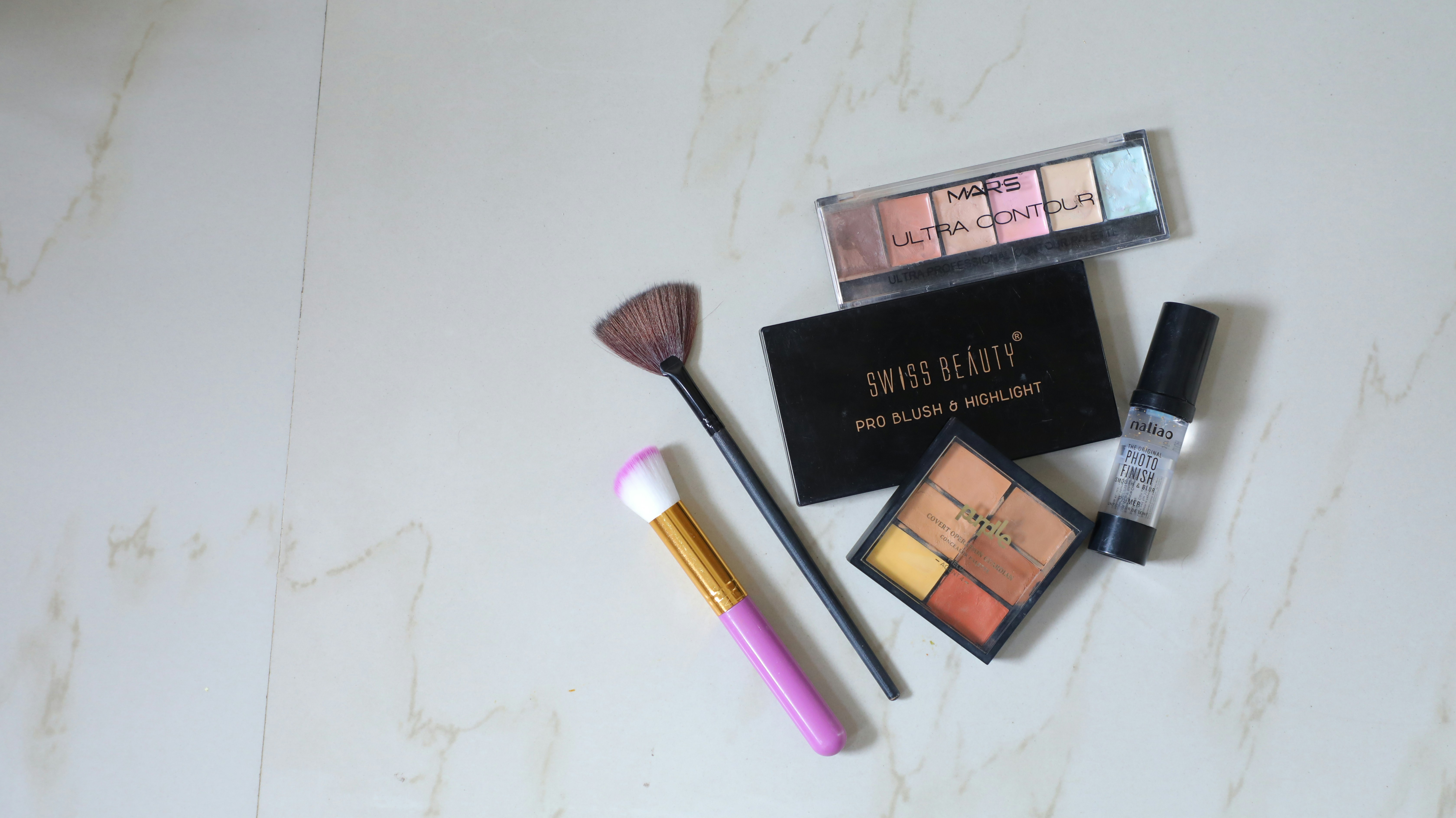 Premium makeup products and brushes arranged on marble, professional studio aesthetic, warm tones