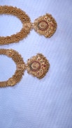 Close-up of a delicate gold necklace with intricate Senegalese patterns on a soft fabric background