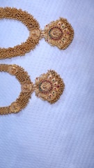 Close-up of a gold kundan bridal necklace resting on rich maroon silk fabric.