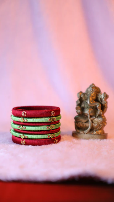 Elegant stack of pastel pink and rose gold bracelets arranged on a white marble surface with subtle shadows