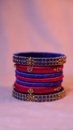 Elegant stack of royal gold bangles with subtle peacock feather motifs on a charcoal background