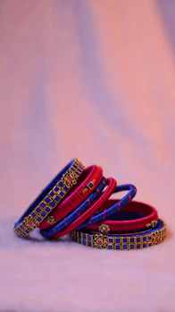 Stacked bangles and bracelets with intricate designs catching the light on a wooden surface.