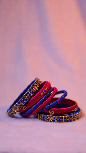 Stacked imitation bangles in vibrant colors arranged artistically on a silk fabric.