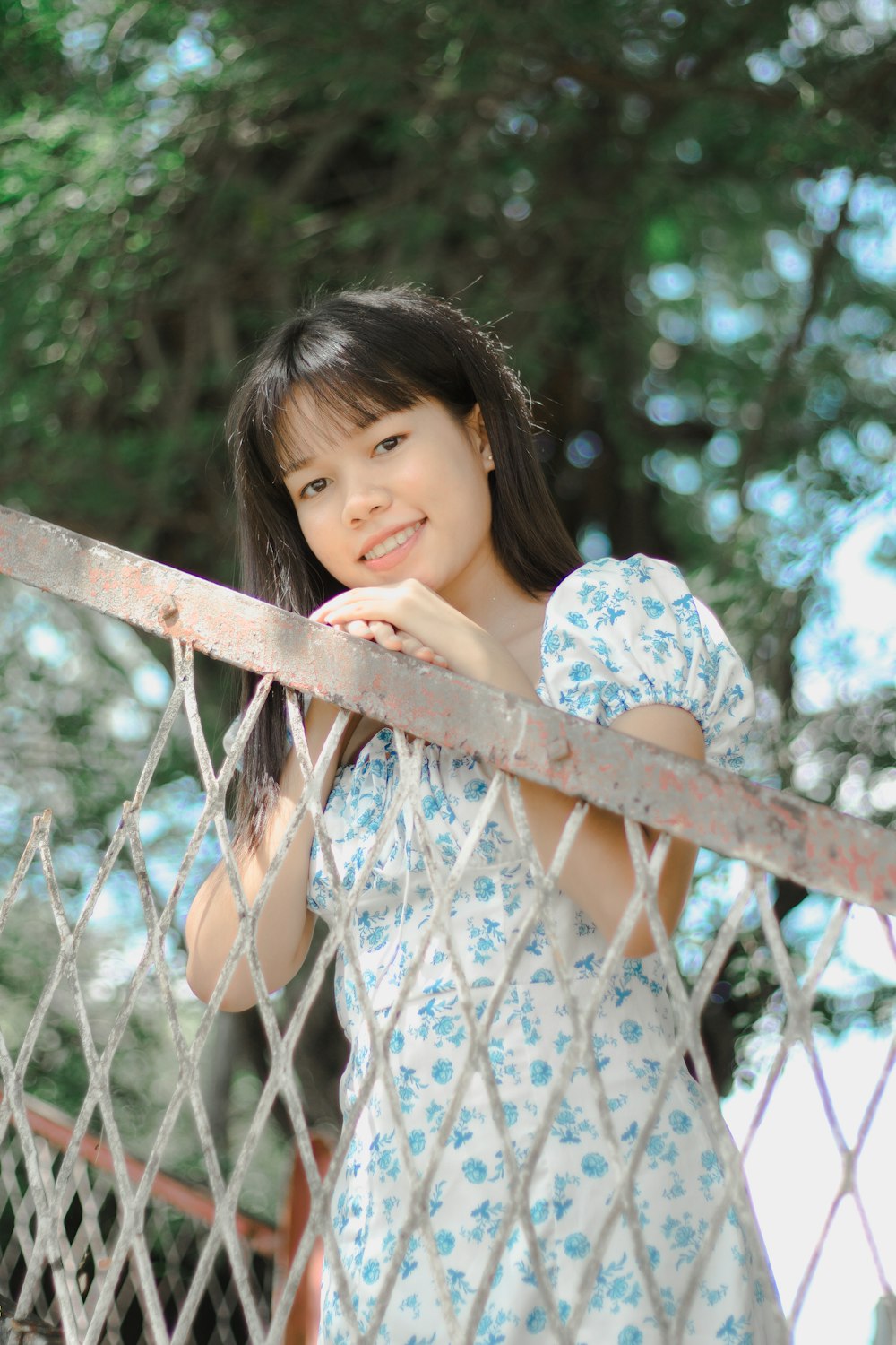 uma menina encostada em uma cerca com a mão no queixo