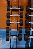 Close-up of a sleek black and red dumbbell set arranged neatly on a rack.
