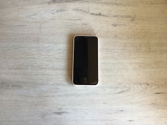 A modern smartphone displayed on a wooden table.