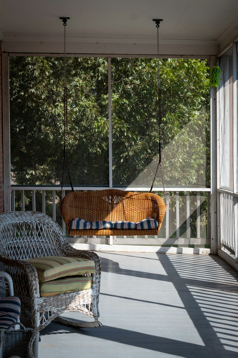 um deck com uma rede e uma cadeira e uma janela com árvores ao fundo