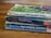 A stack of three worn paperback books is lying on a wooden surface. The books have visibly aged covers with scuffed edges and faded colors. They are authored by C.S. Lewis and include titles such as 'Out of the Silent Planet', 'Perelandra', and 'That Hideous Strength'. The top book has a green cover with abstract patterns, while the other two have predominantly blue covers.