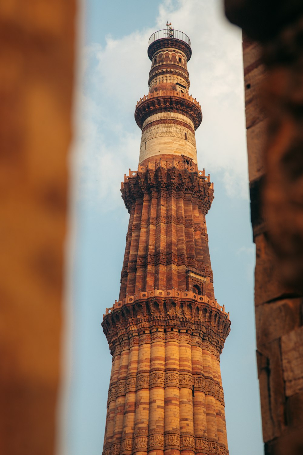 a tall tower with a pointed top with Qutub Minar in the background
