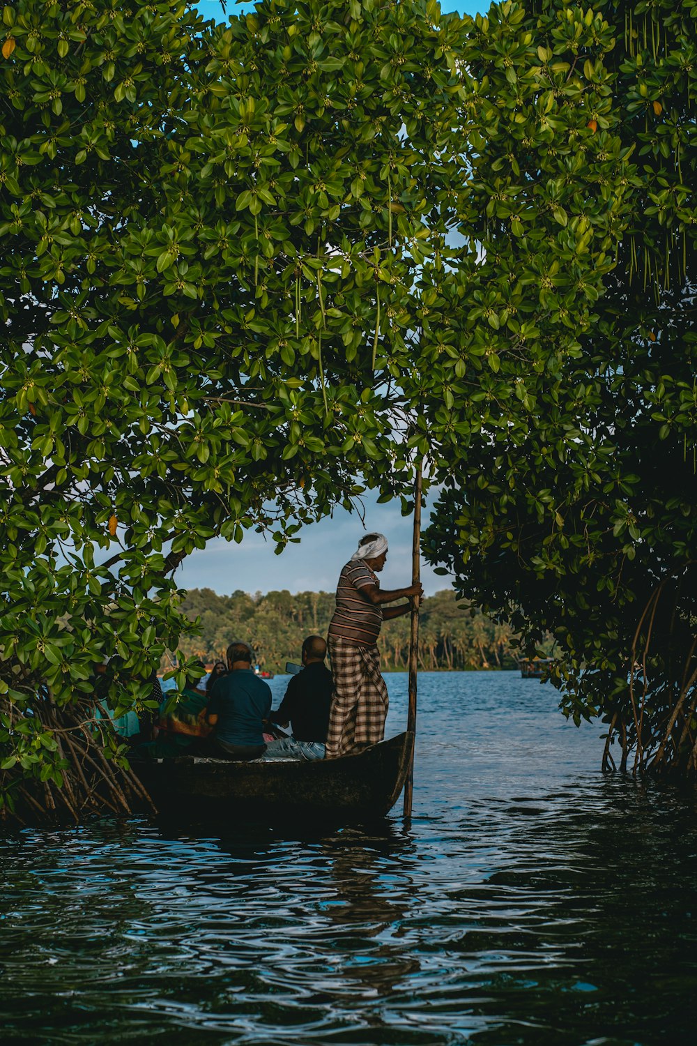 une personne sur un bateau dans une rivière avec des gens à bord