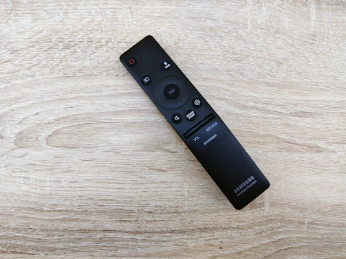Close-up of a sleek remote control for automated curtains on a wooden table.
