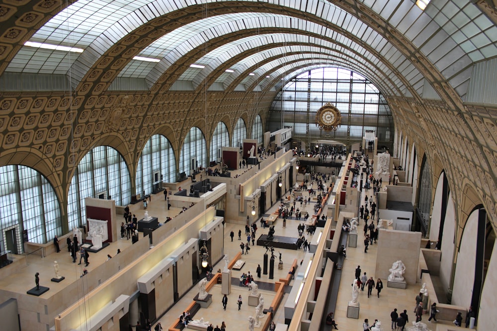 a large room with many people and windows with Musée d'Orsay in the background