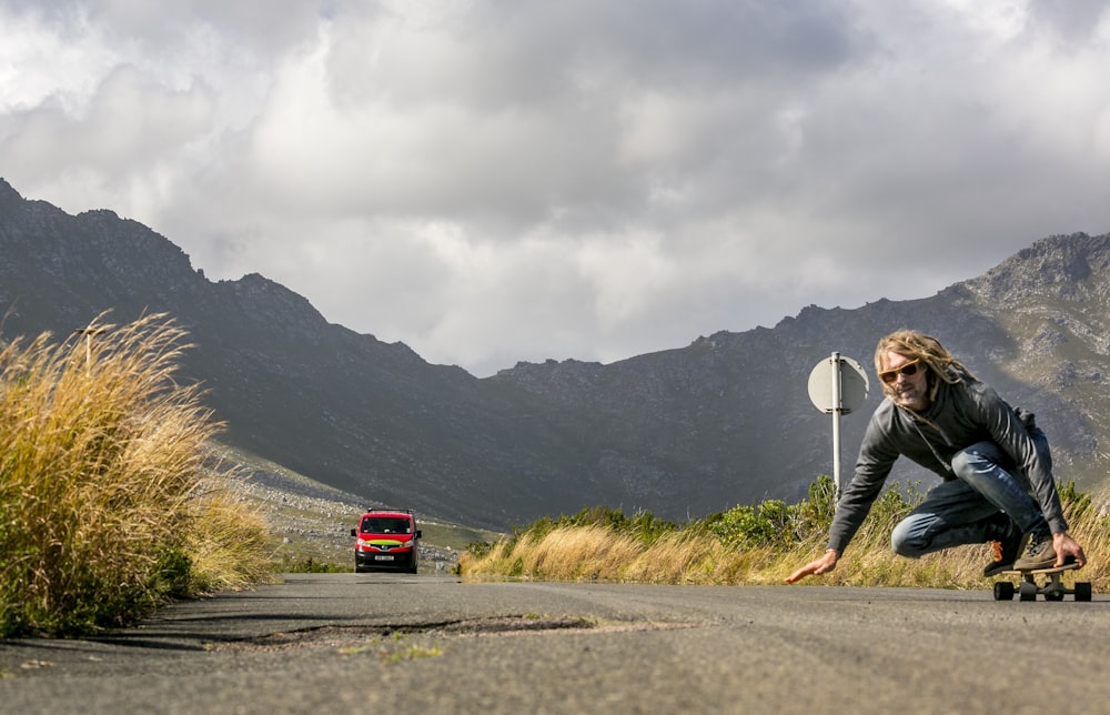 a person kneeling on a road with a skateboard
