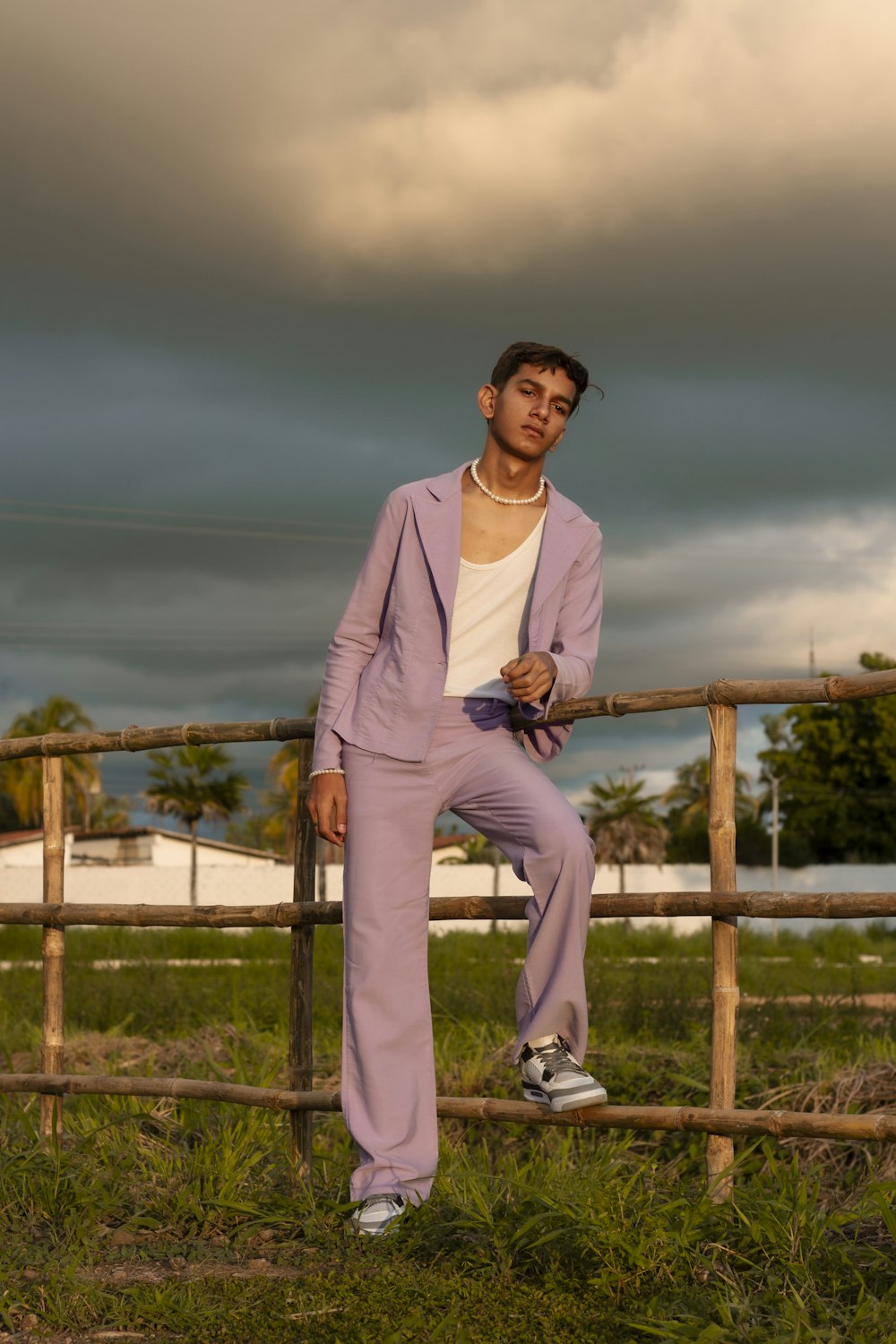 a man in pink suit leaning on a fence