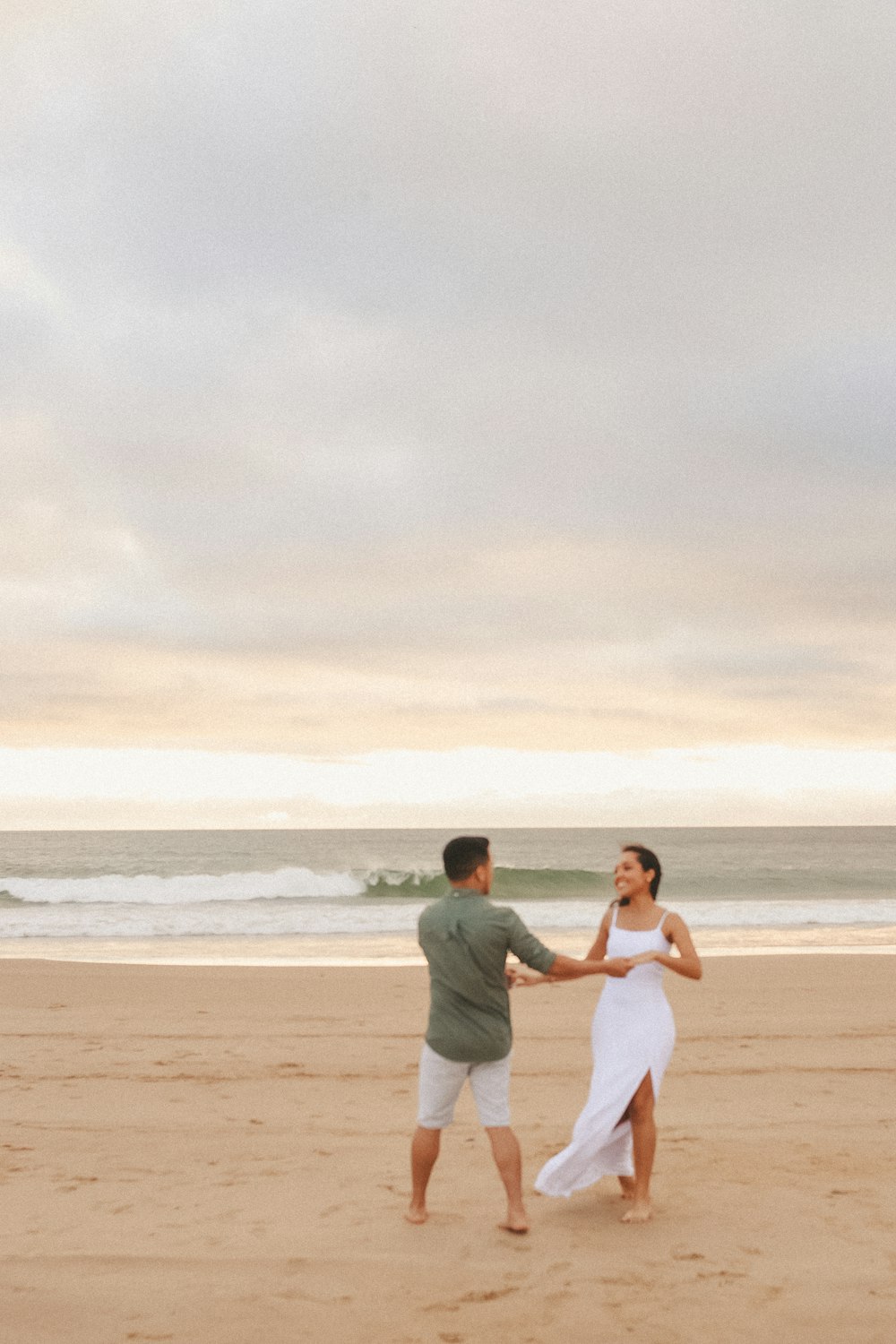 a man and woman holding hands on a beach