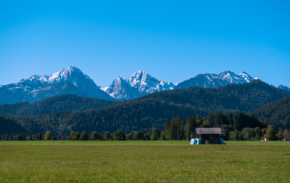a small house in a field with mountains in the background