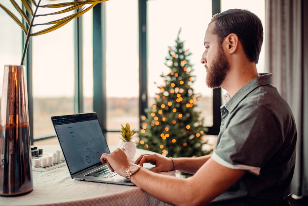 eine Person, die an einem Tisch mit einem Laptop und einer Vase voller Blumen sitzt