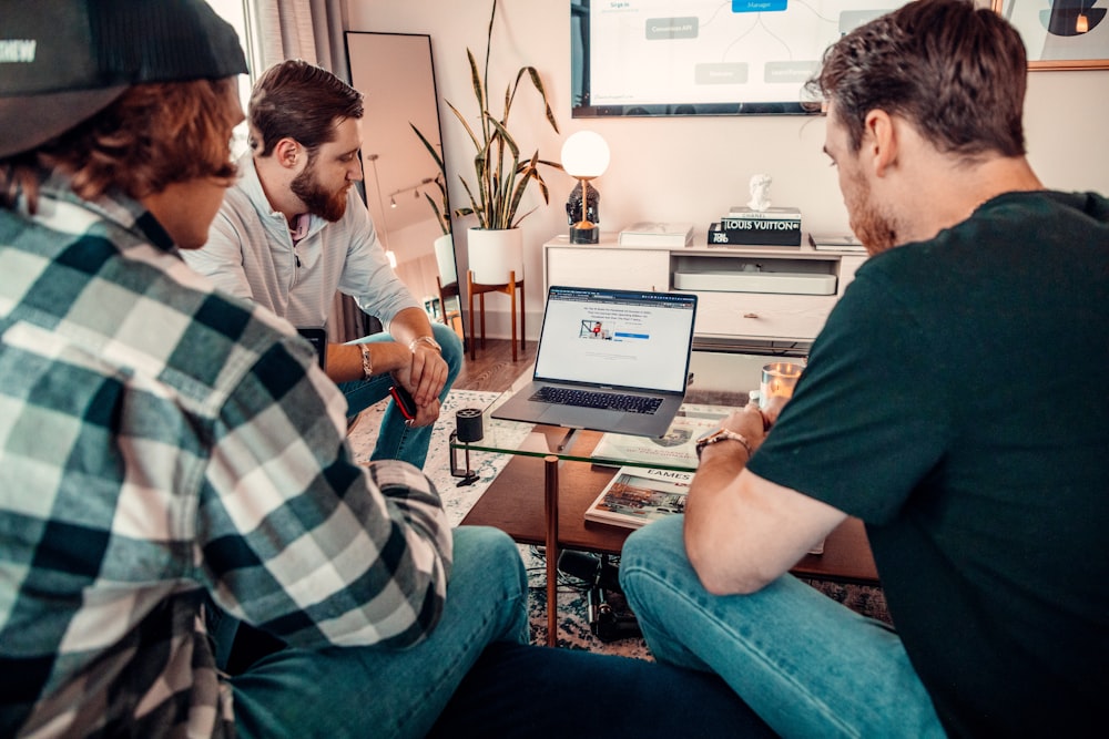 a group of men sitting around a table with a laptop