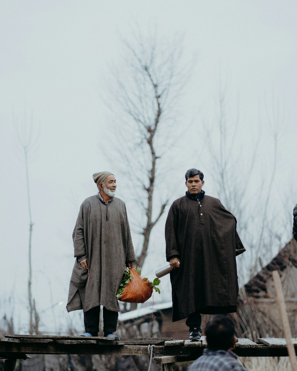 a man and woman walking on a bridge with a tree in the background