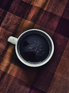 A warm terracotta-hued cup of coffee half-drunk atop textured paper.